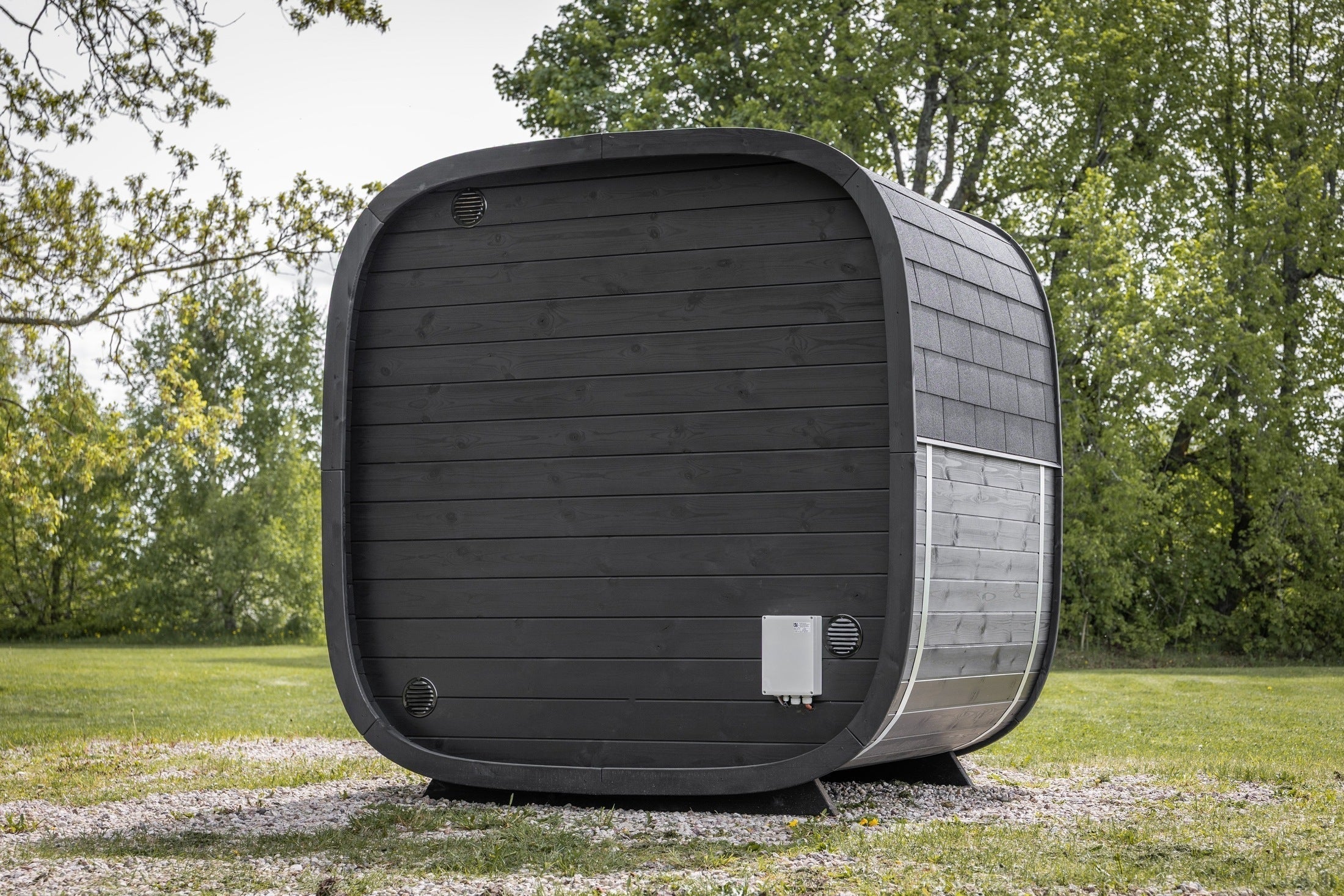 Leil Black Cube Classic backyard sauna with modern black exterior, Thermowood construction, natural alder interior, and relaxing LED ambient lighting